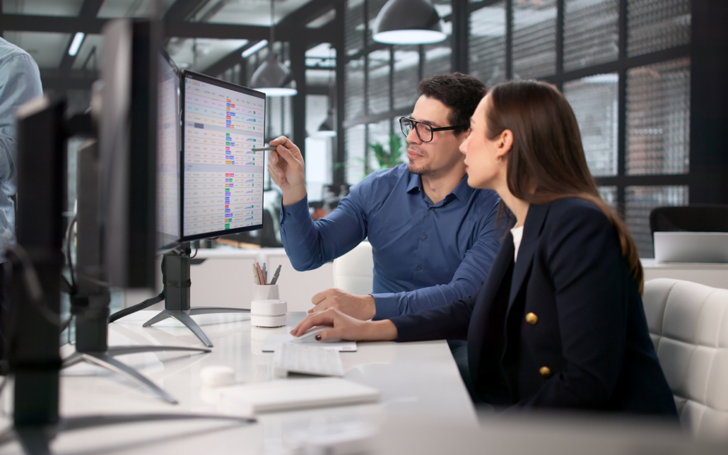 Two Workers Looking At Information On Computer