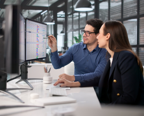 Two Workers Looking At Information On Computer